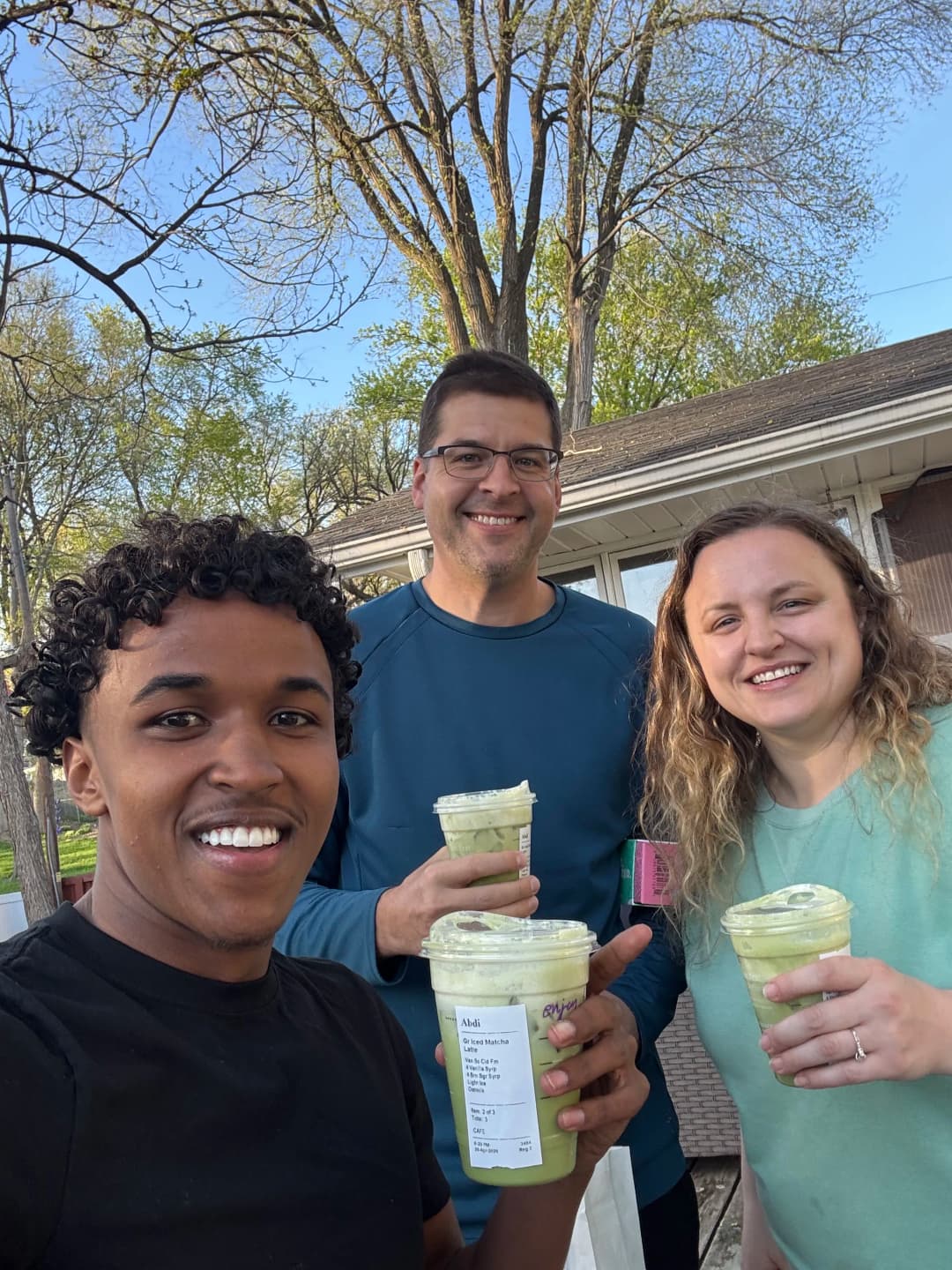 Group enjoying green smoothies outdoors in spring sunshine. Smiling faces and vibrant greenery.